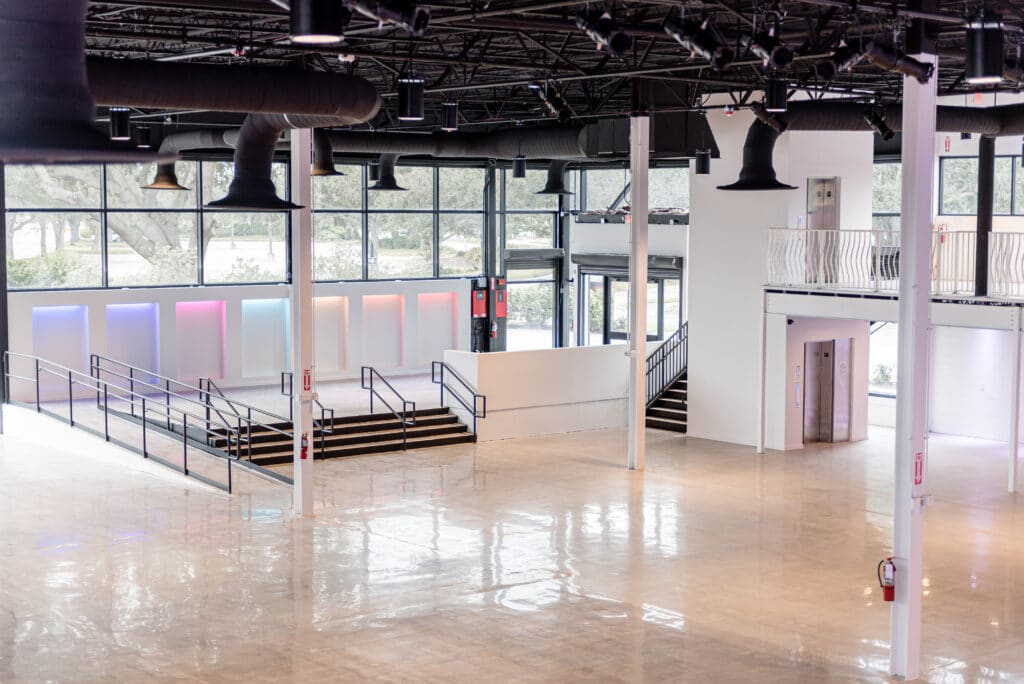 interior event space with wood floors, large windows, white columns and black ceiling