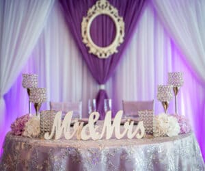 white canopy with purple lighting over sweetheart table with mr and mrs sign