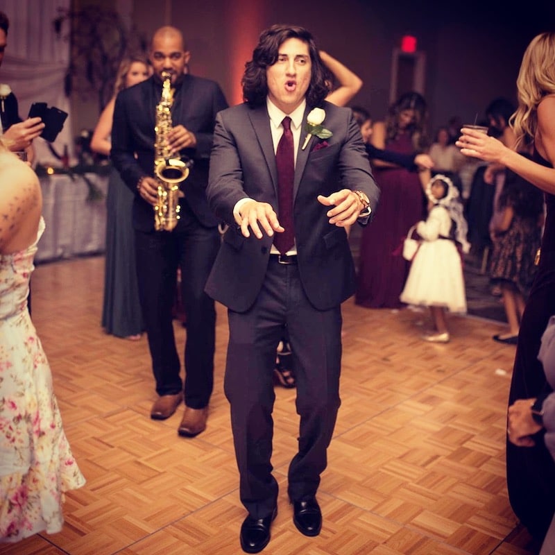 wedding guests dance while saxophone player performs on the dance floor