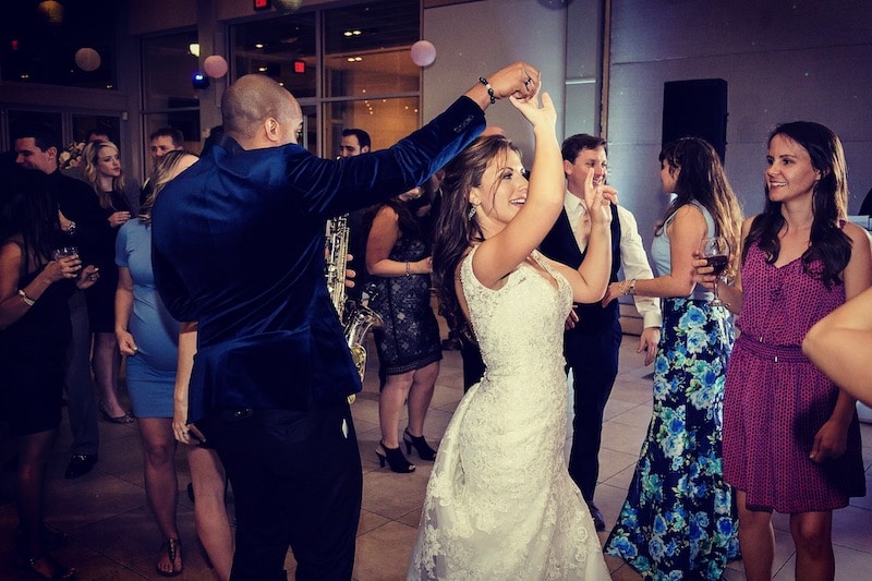 saxophone player spins and dances with bride while he plays his sax