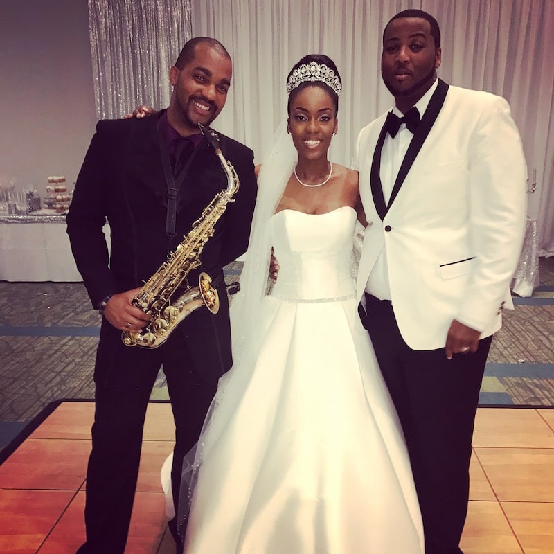 saxophone player standing next to bride and groom on the dance floor during their wedding reception