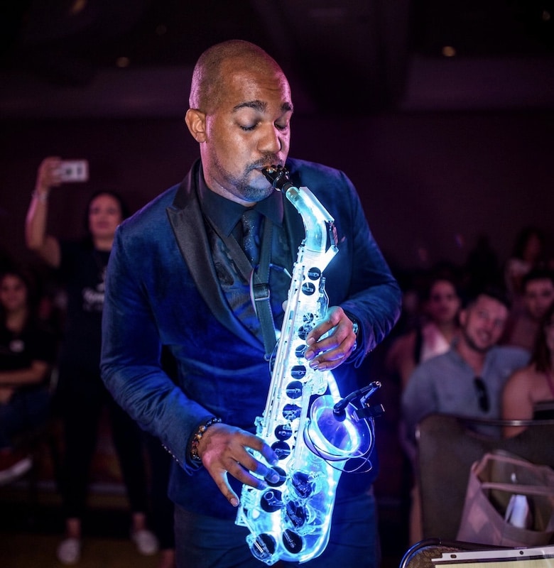 saxophone player performing at night with a lit up led saxophone