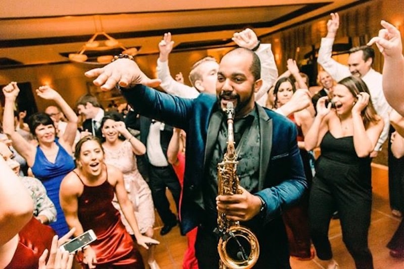 saxophone player leading the crowd in a fun dance during wedding reception