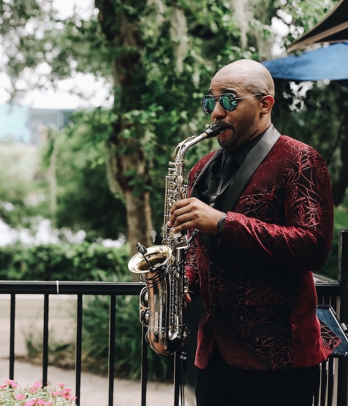 RLE3 Music saxophone player in a red tux coat performing outside while wearing aviator glasses