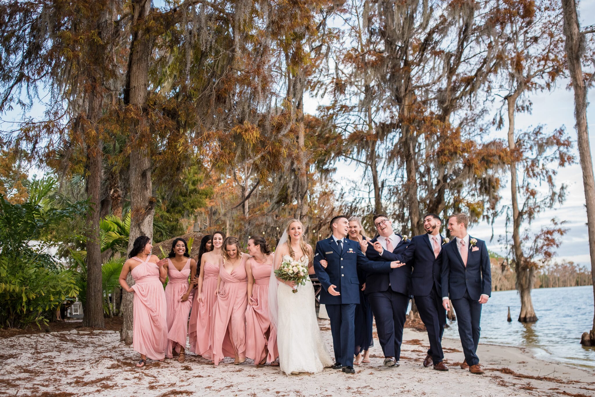 wedding party standing under trees on beach