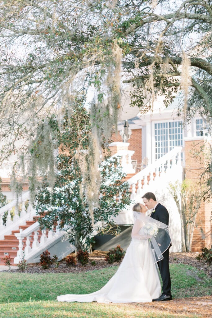 bride and groom kissing under moss covered tree