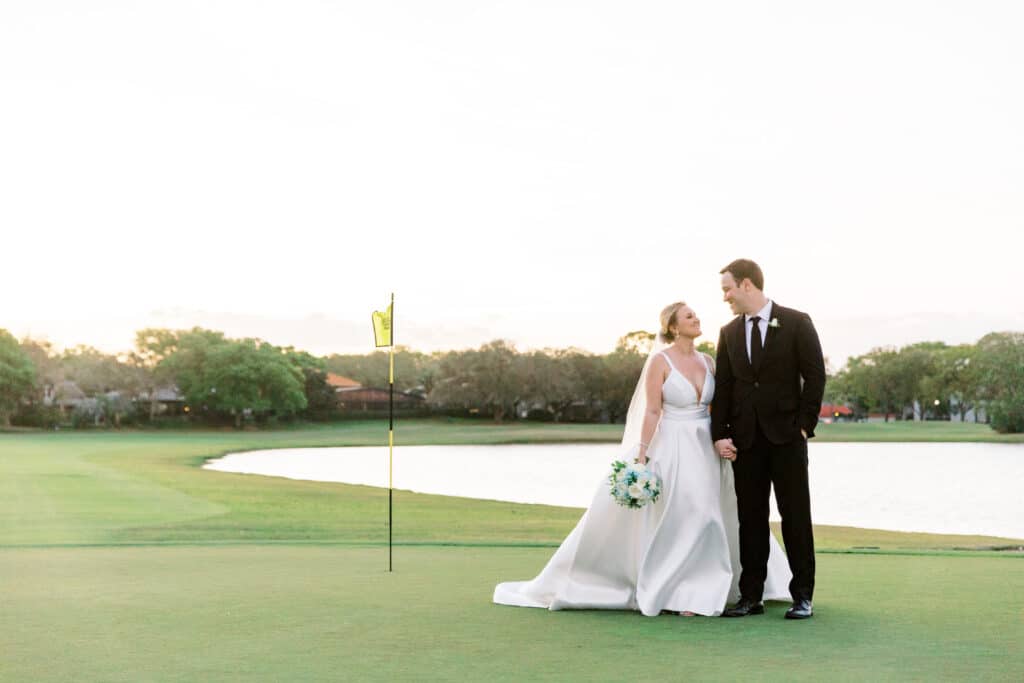 bride and groom standing on green of golf course