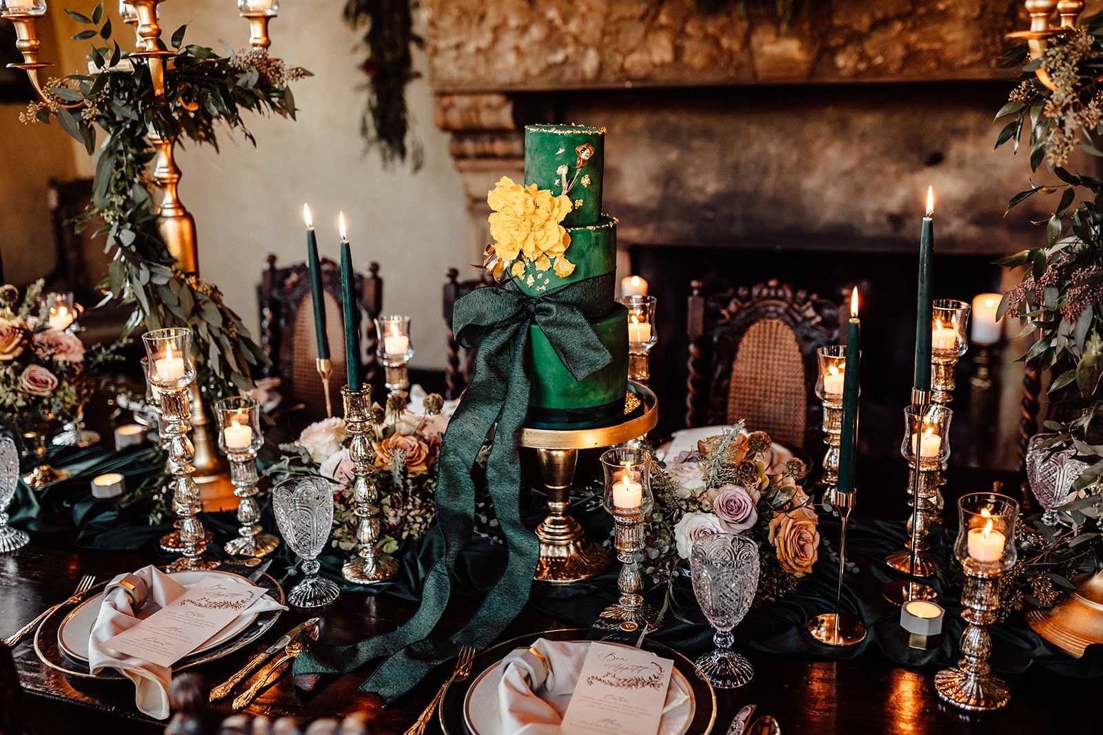 emerald green cake in the middle of wedding decorated table with elegant emerald green and gold decor cake with giant emerald green bow on the bottom tier