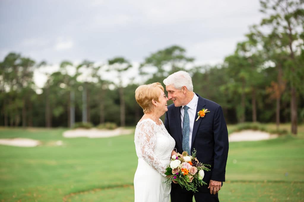 married couple stares at each other on wedding day outside on golf course at wedding venue for portraits