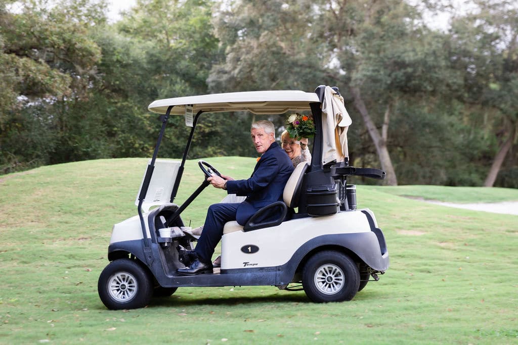 newlywed couple on golf cart at wedding venue driving on golf course