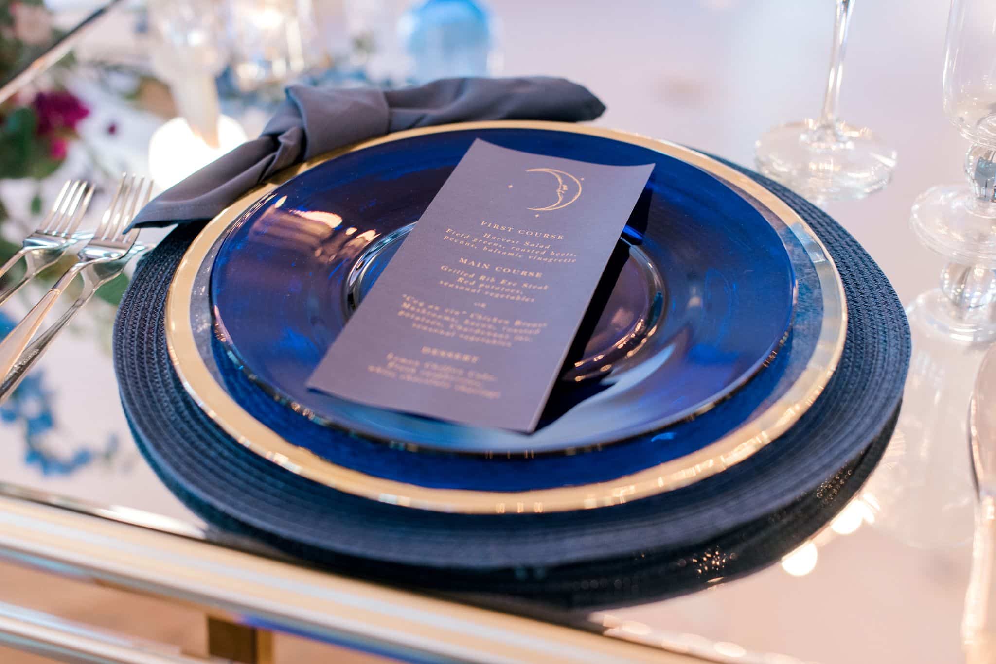calligraphy menu on top of table setting with over the moon celestial theme on reflective tabletop
