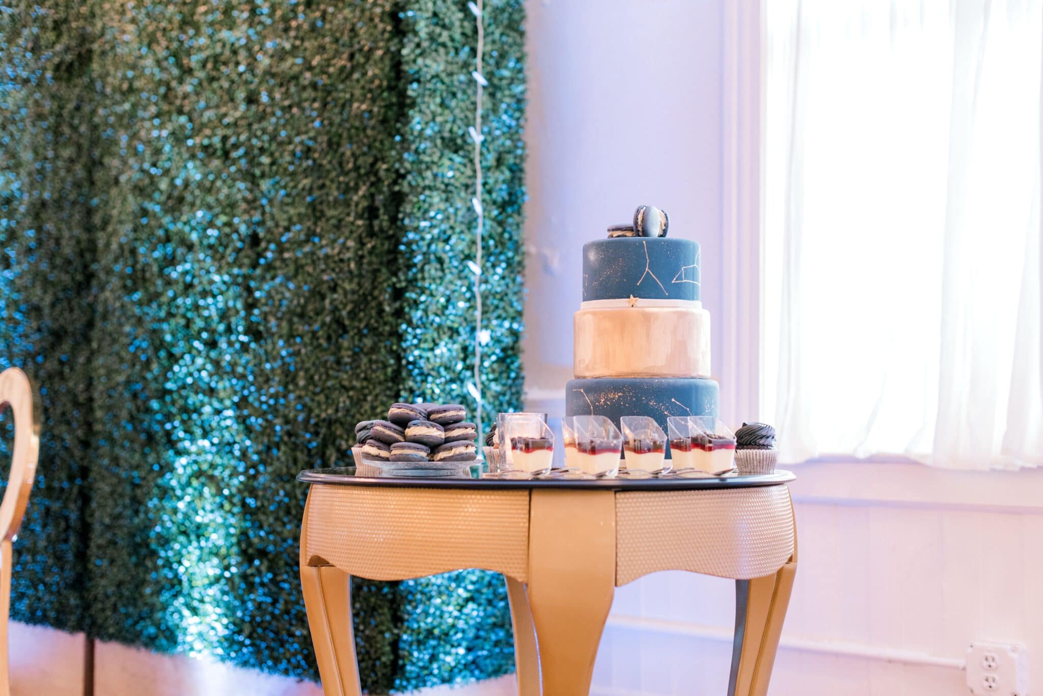 dessert table at wedding in front of hedge wall with constellation decorated cake and other galaxy decorated baked goods