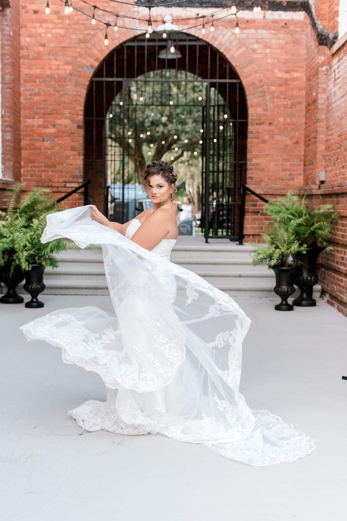 bride in wedding dress and flowing bottom in front of signature photo spot at wedding venue