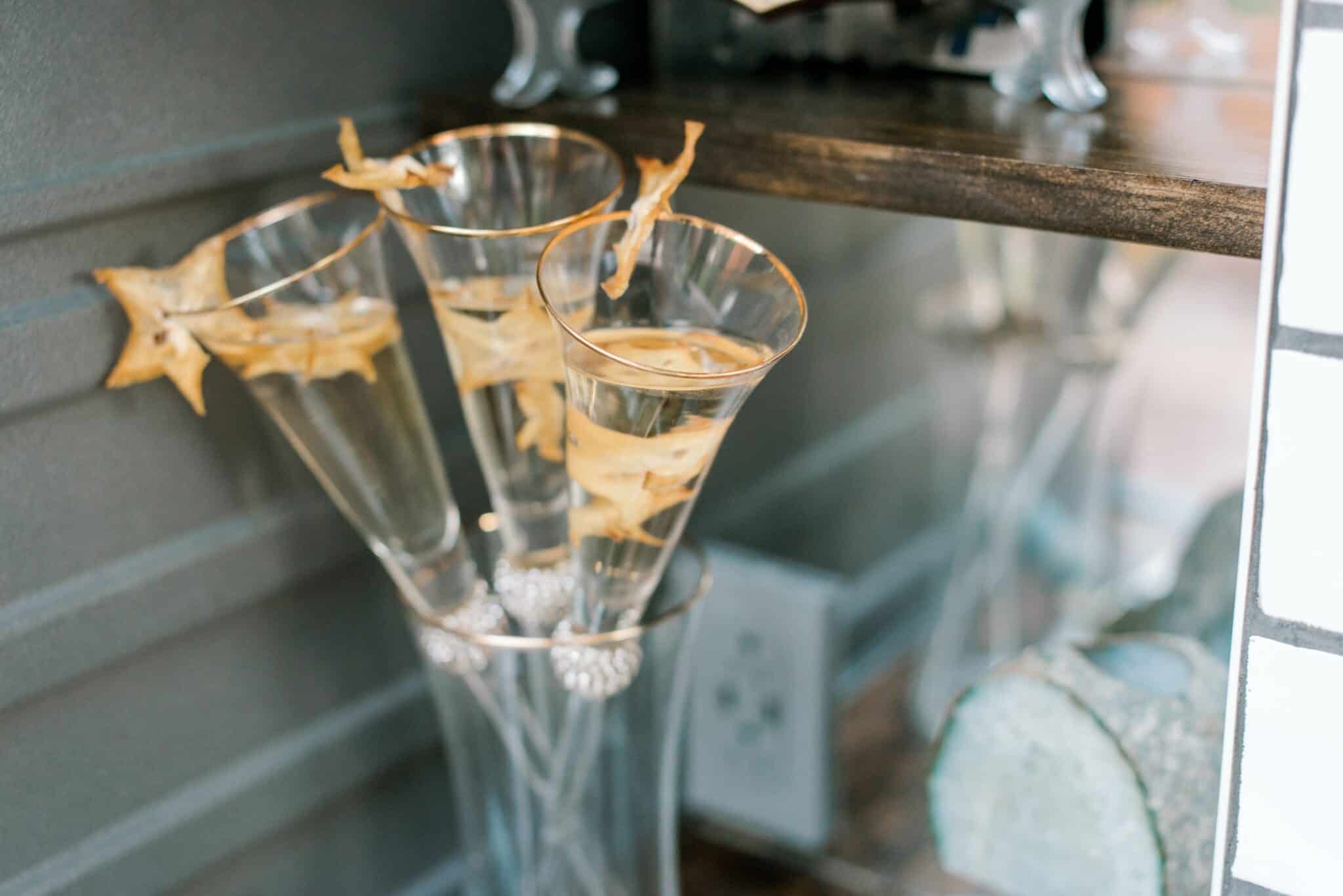close up of tall champagne glasses decorated with starfruit inside the glass and on the edge