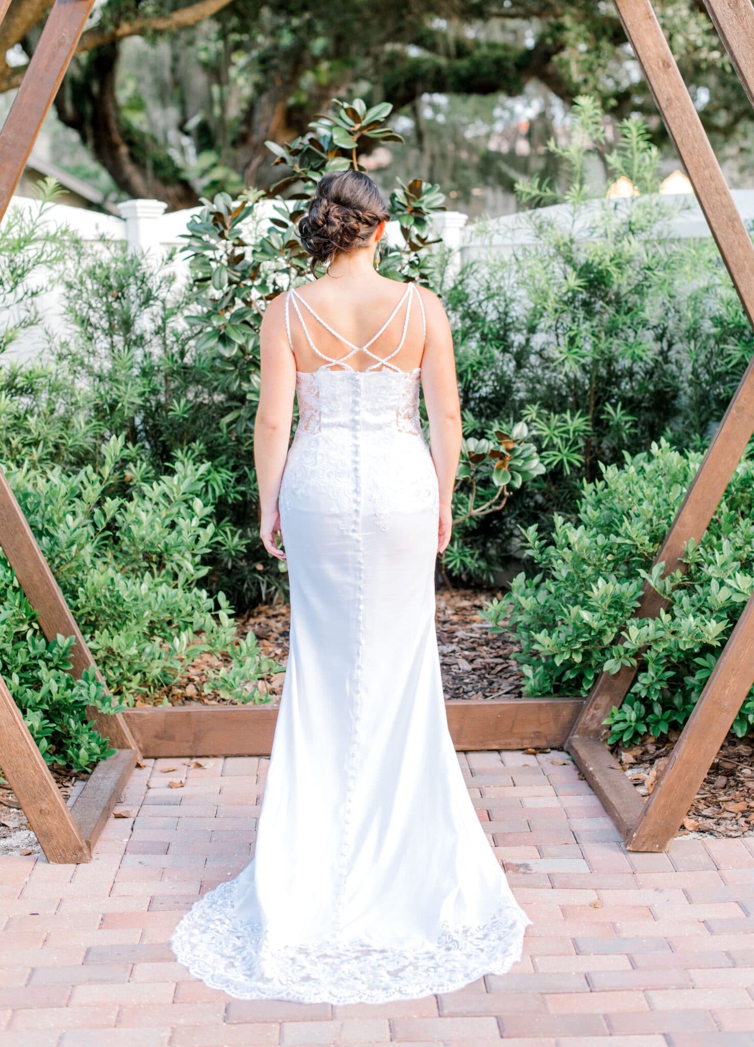 detailed back of bridal gown outside surrounded by greenery at local wedding venue