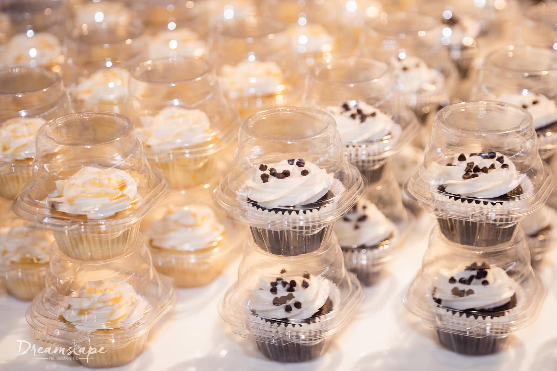 close up of vanilla and chocolate cupcakes in individual packages stacked on a table