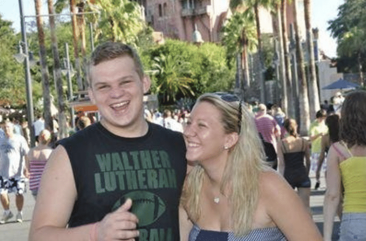 blonde haired girl laughs with strapless shirt on next to boy smiling big with cut off sleeve black shirt in front of disneys tower of terror