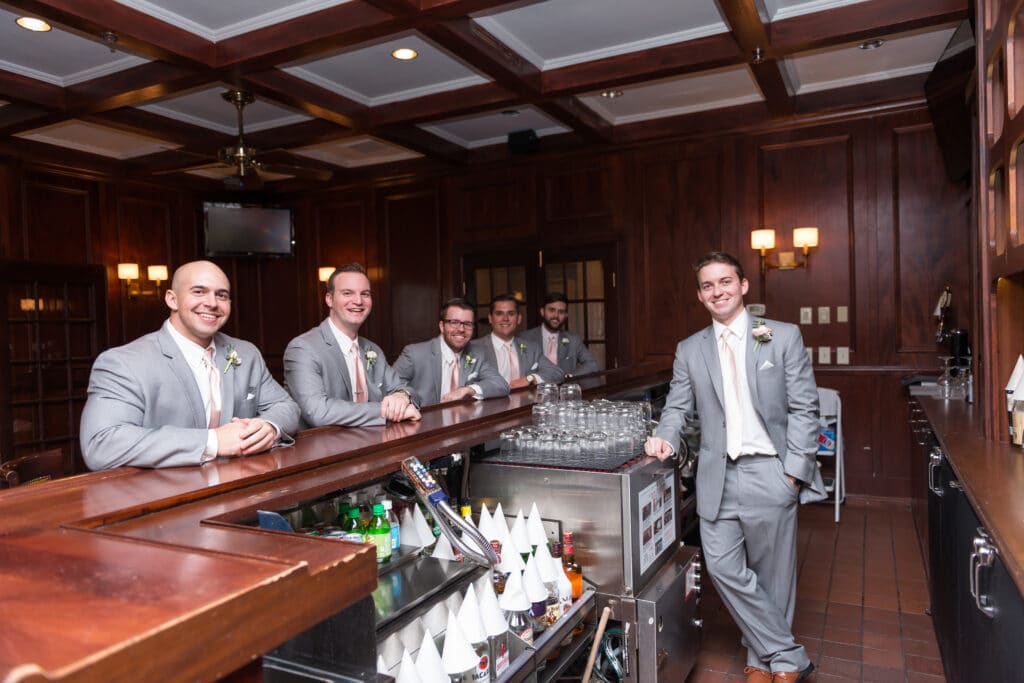 groom standing behind the bar with groomsmen sitting at the bar