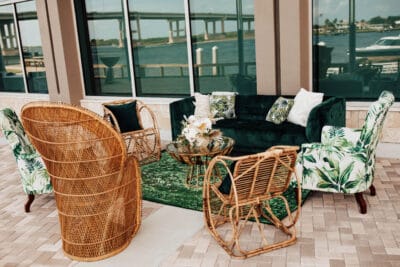 green and rattan tropical furniture set up on patio for event at brannon center in florida overlooking the water