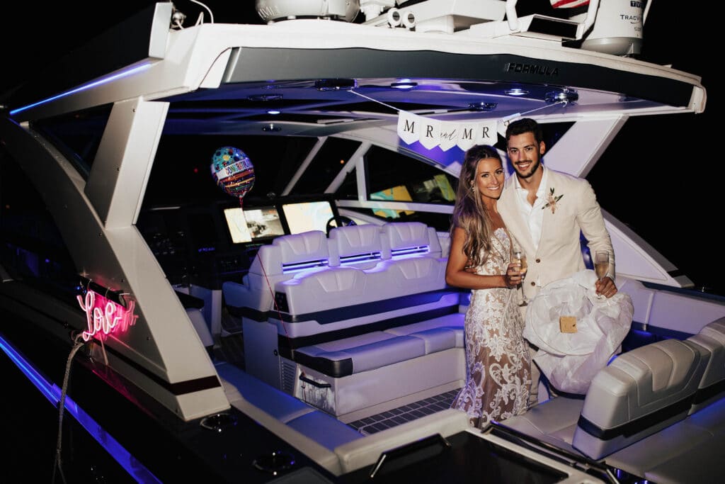 newlywed bride and groom holding glasses of champagne on private boat