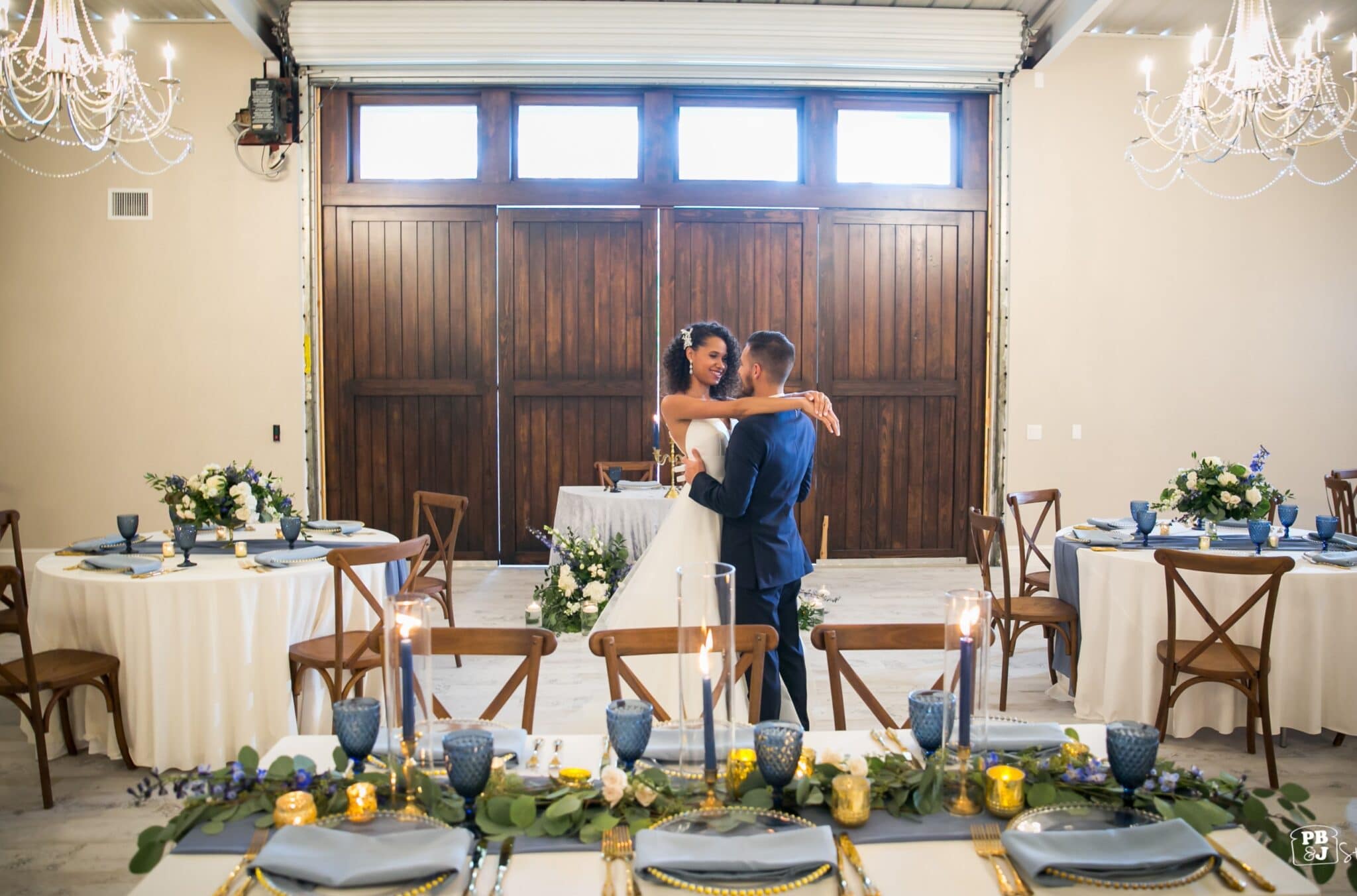 bride and groom dancing in barn below chandeliers