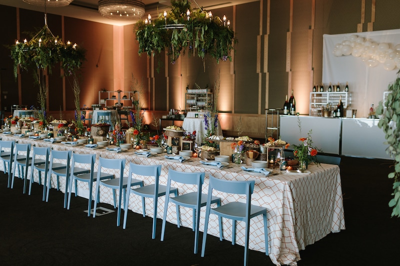 long table setup at wedding reception with matching blue chairs