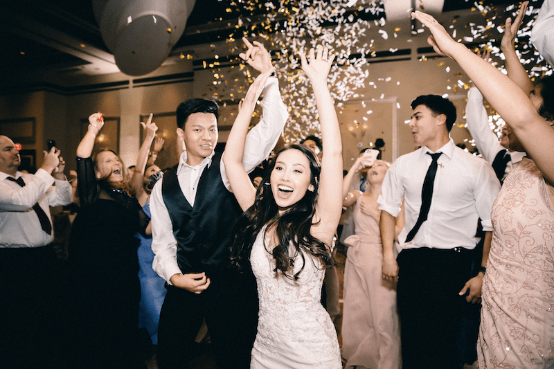 bride and groom celebrating while guests shower them with confetti