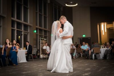 bride and groom dancing in ballroom with guests seated at their tables watching