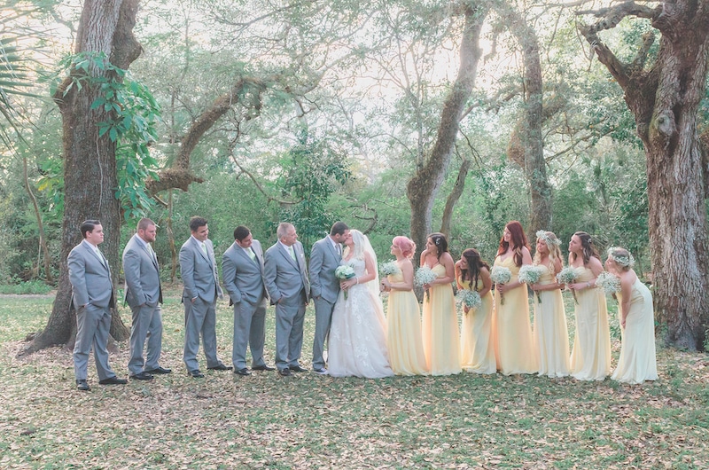 bride and groom kissing while bridal party leans in to watch