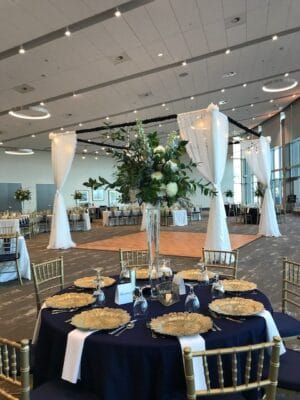 round table with black tablecloth and gold place settings with large floral centerpiece for wedding reception in brannon center ballroom