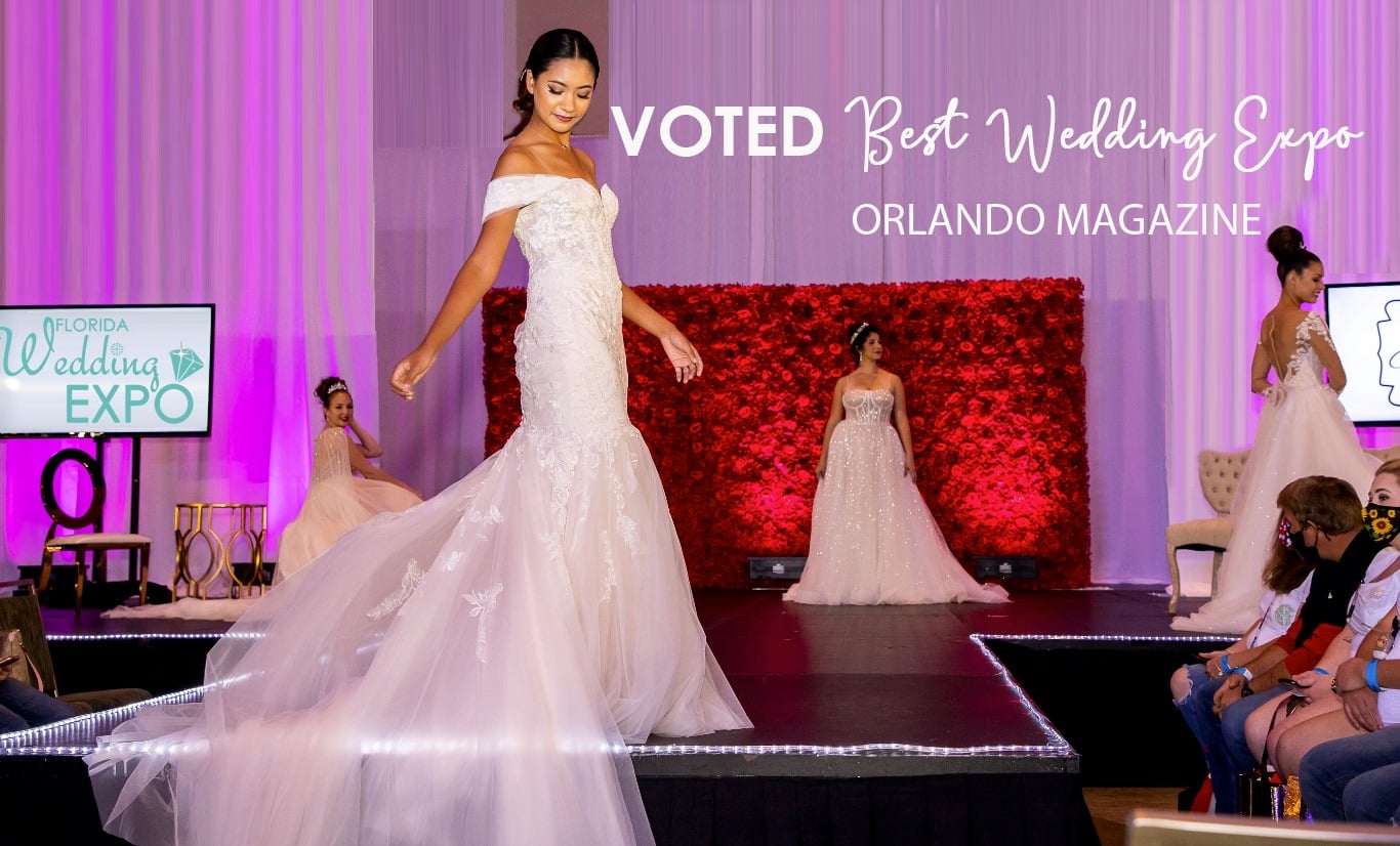 woman in wedding dresses on fashion show stage at wedding show with red rose wall at the back of the stage