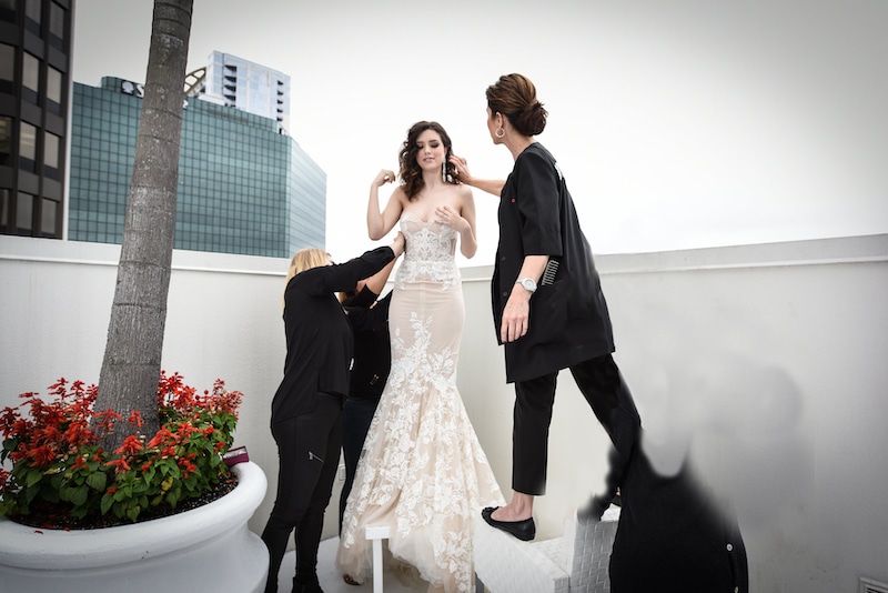 hair and makeup team standing on chairs and attending to bride to make sure she is picture perfect
