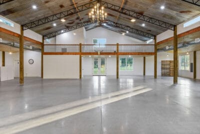 interior of white barn event space with wood rafters and beautiful chandeliers