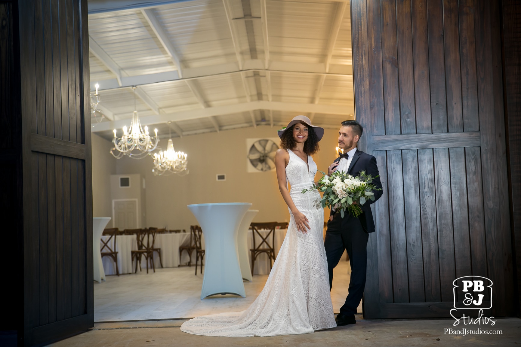 bride and groom posing outside of large wooden barn doors at Cypress Creek Farmhouse