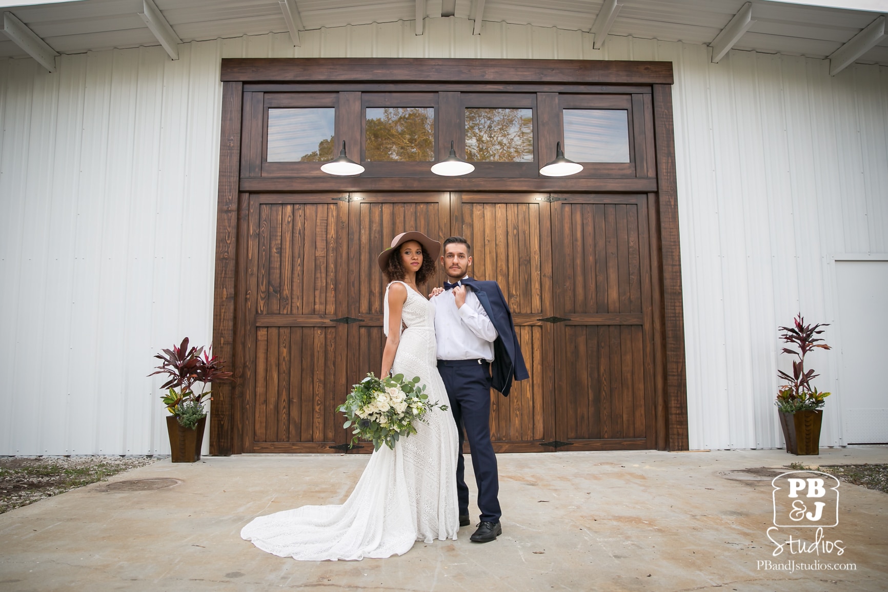 bride and groom standing in front of large dark wooden doors at Cypress Creek Farmhouse