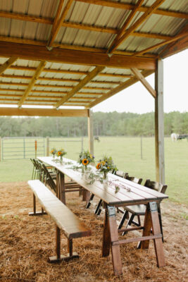 long tables, benches, and chairs set up for guests at a wedding reception on a farm