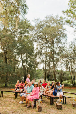 guests seated at outdoor wedding on dark wood benches