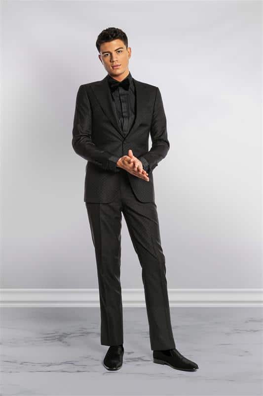 man in an all black patterned suit, with matching black shoes, shirt, and bow tie