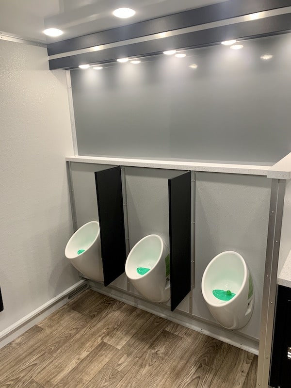row of clean urinals inside of rented restroom from Luxe Flush