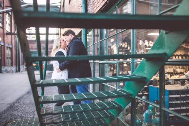 looking through green metal stairs outside of building at couple standing together looking at each other