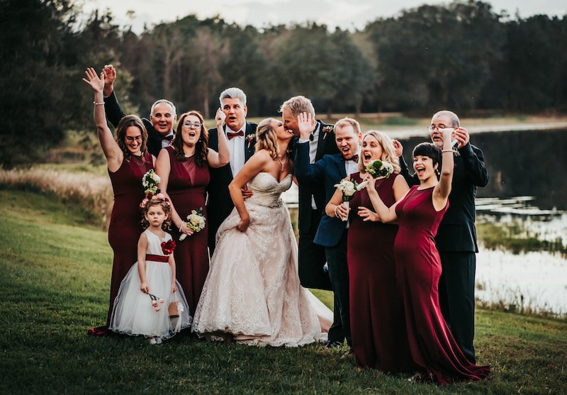 bride and groom kissing while their bridal party cheers