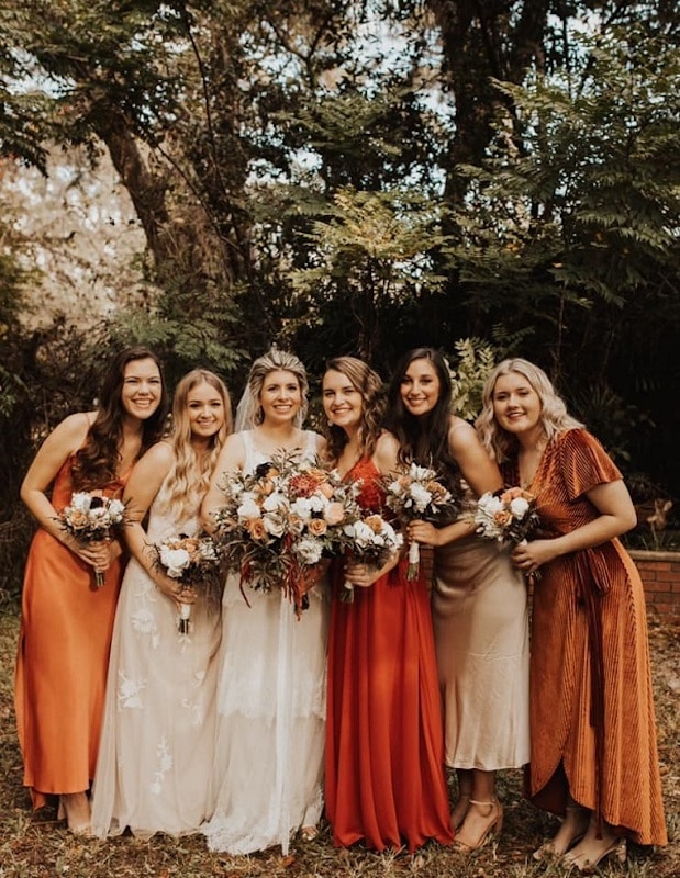 bride standing with her bridesmaids while everyone holds their flower bouquets