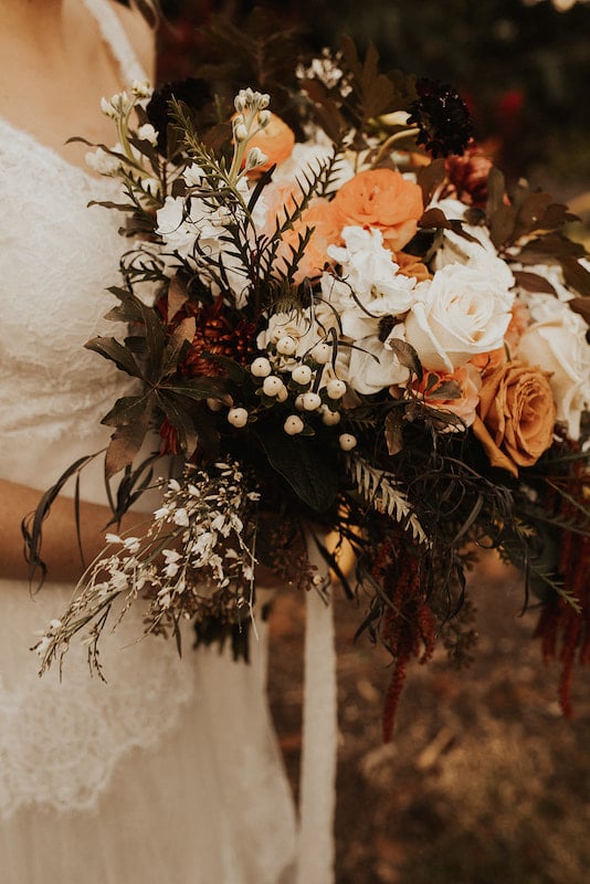 bride holding her flower bouquet with white and orange flowers