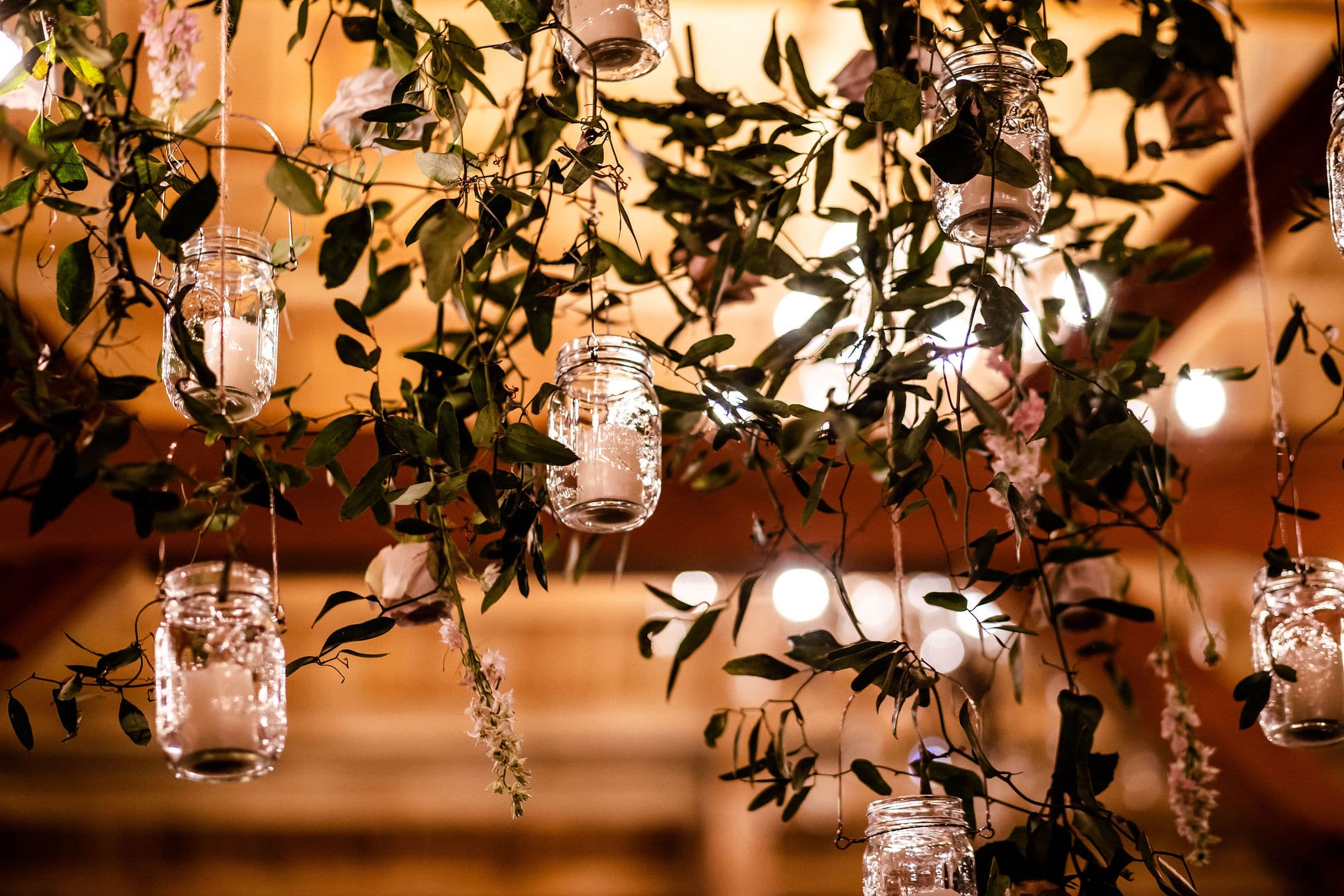 greenery and miniature jars with candles inside hang down from ladder as decoration for ethereal wedding inspiration