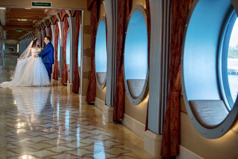 bride and groom walking through a hallway on a large cruise ship
