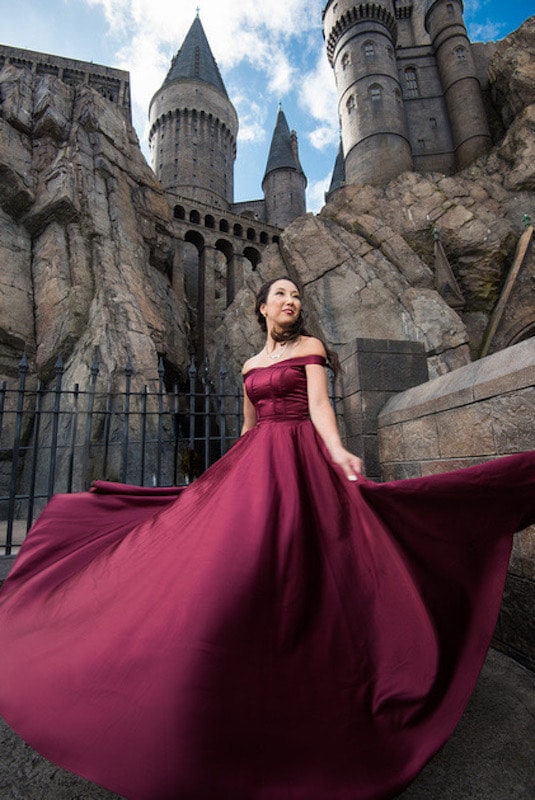 woman in burgundy dress twirling with Hogwarts in the distance behind her