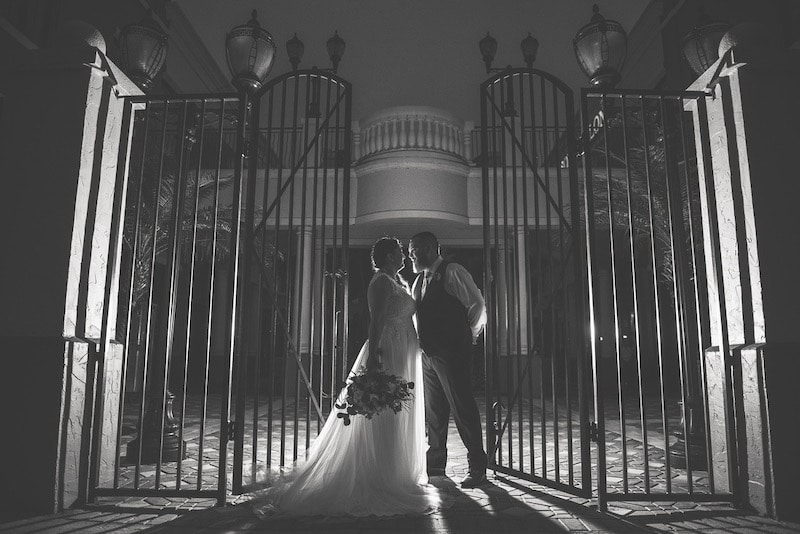 bride and groom standing in the middle of a large iron gate