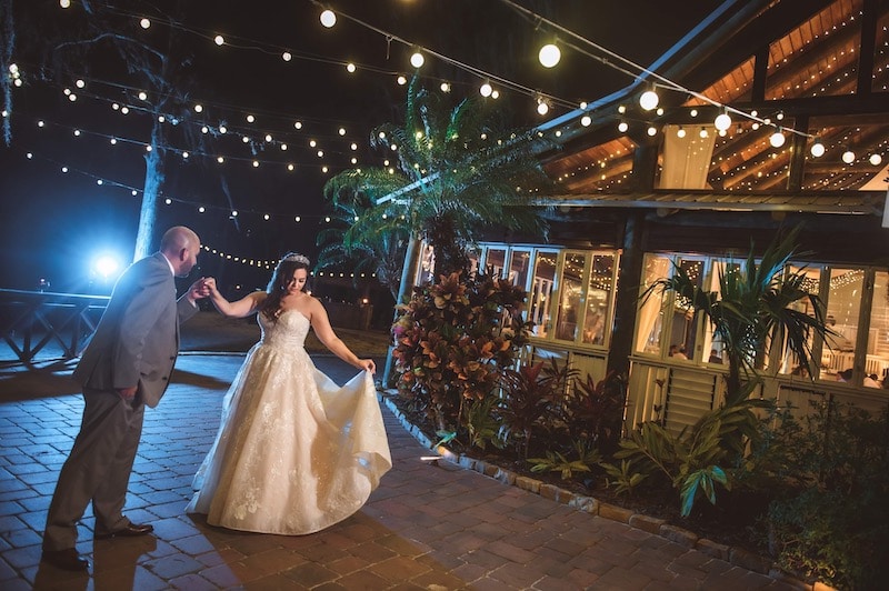 bride and groom dancing outside and night under market lighting