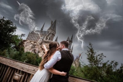 bride and groom kissing while shooting lightning out of their magic wands and Hogwarts is in the distance