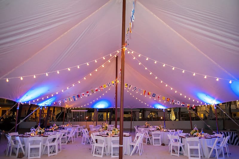 outdoor wedding reception set up underneath a tent with market lighting